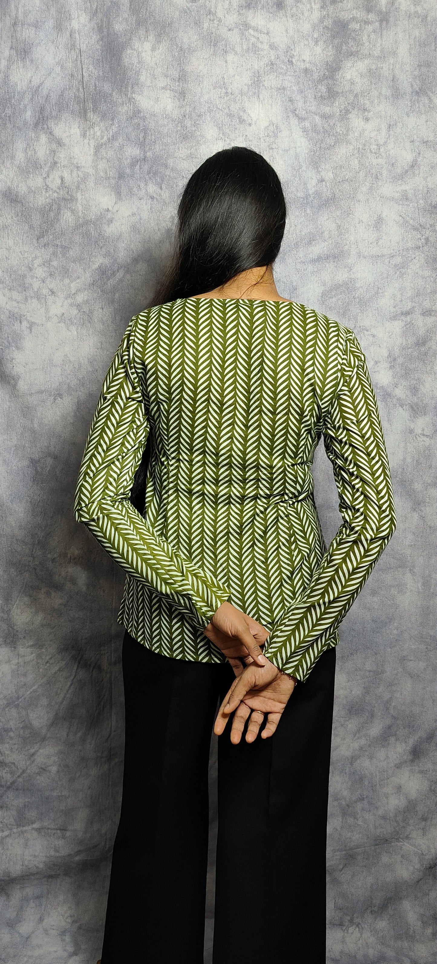Person wearing a green patterned kurti against a gray background