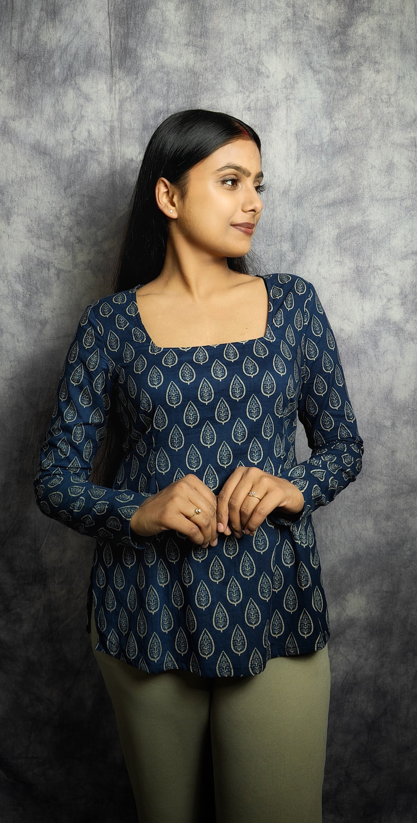 Woman wearing a blue patterned top against a gray background
