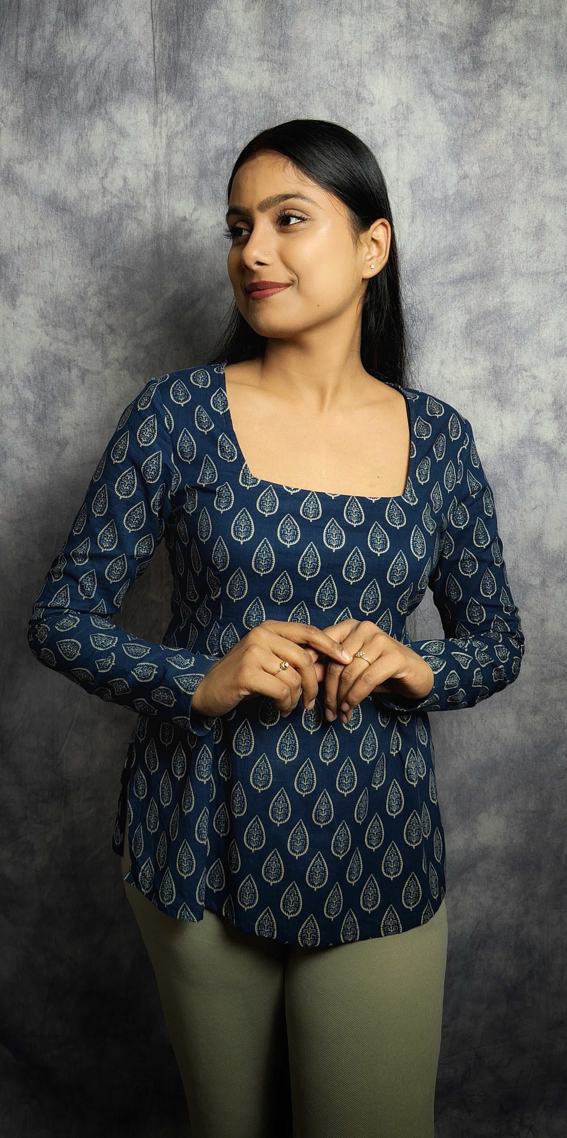 Woman wearing a blue patterned top against a gray background