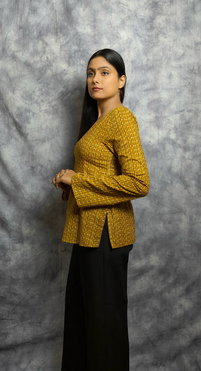 Woman wearing a mustard yellow textured top against a gray background