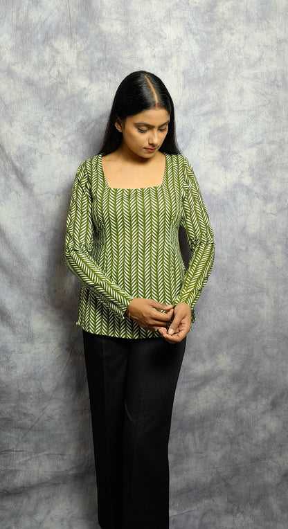 Woman wearing a green patterned top against a gray background