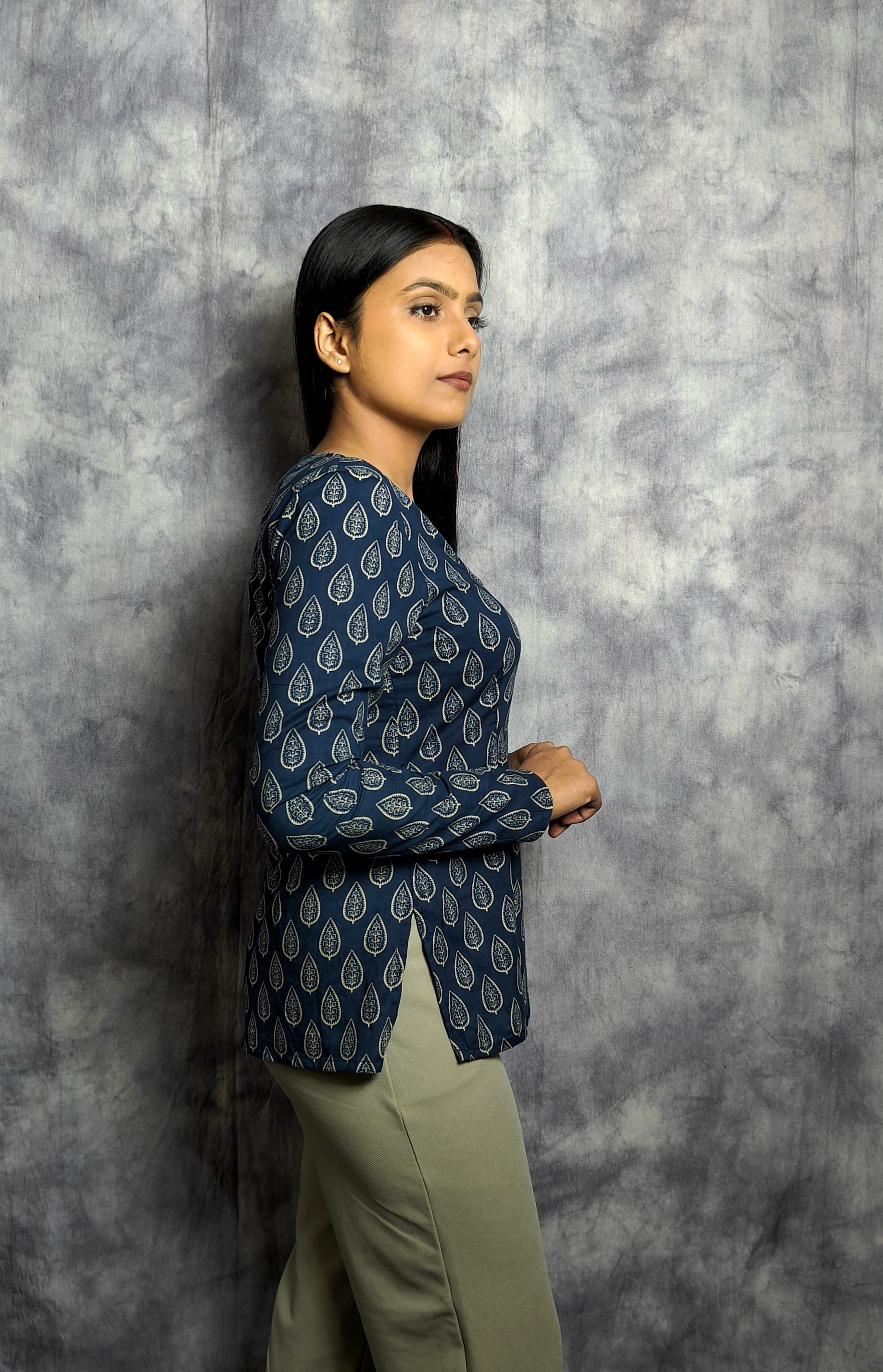 Woman wearing a blue patterned top against a gray textured background
